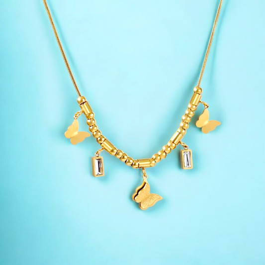 A gold plated necklace with shimmer butterfly charms and a CZ pendant, displayed against a blue background.